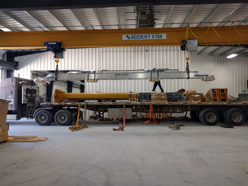 top running bridge crane being handled by underhung overhead crane.