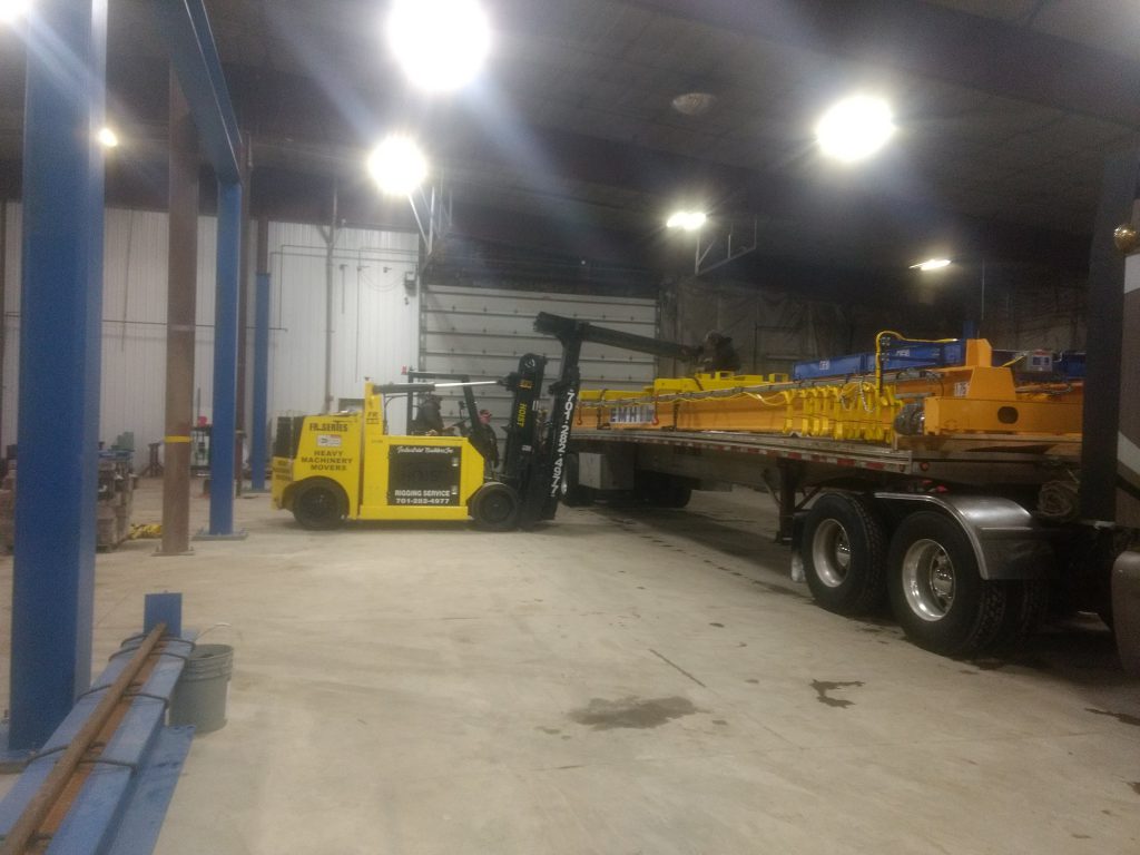 forklift moving crane parts off of truck